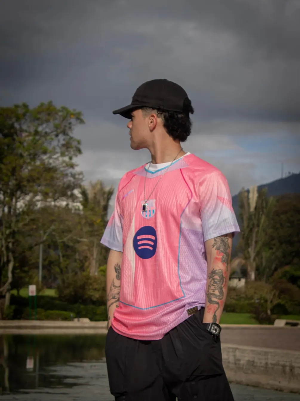 David Vega de espaldas con camiseta rosa junto a un lago