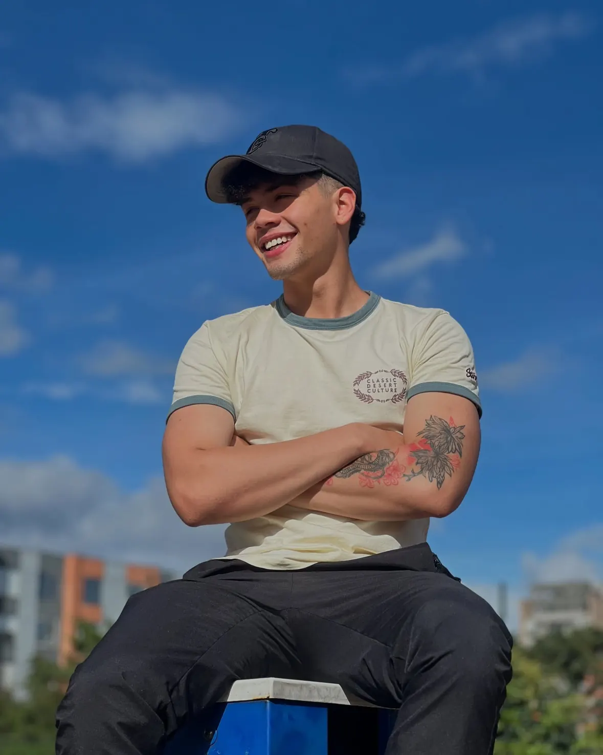 David Vega sonriendo con gorra y brazos cruzados bajo el cielo azul