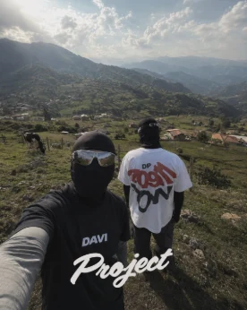 Selfie de dos personas con pasamontañas y camisetas Project en la montaña