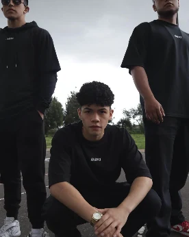 David Vega agachado con camiseta negra DAVI junto a dos amigos